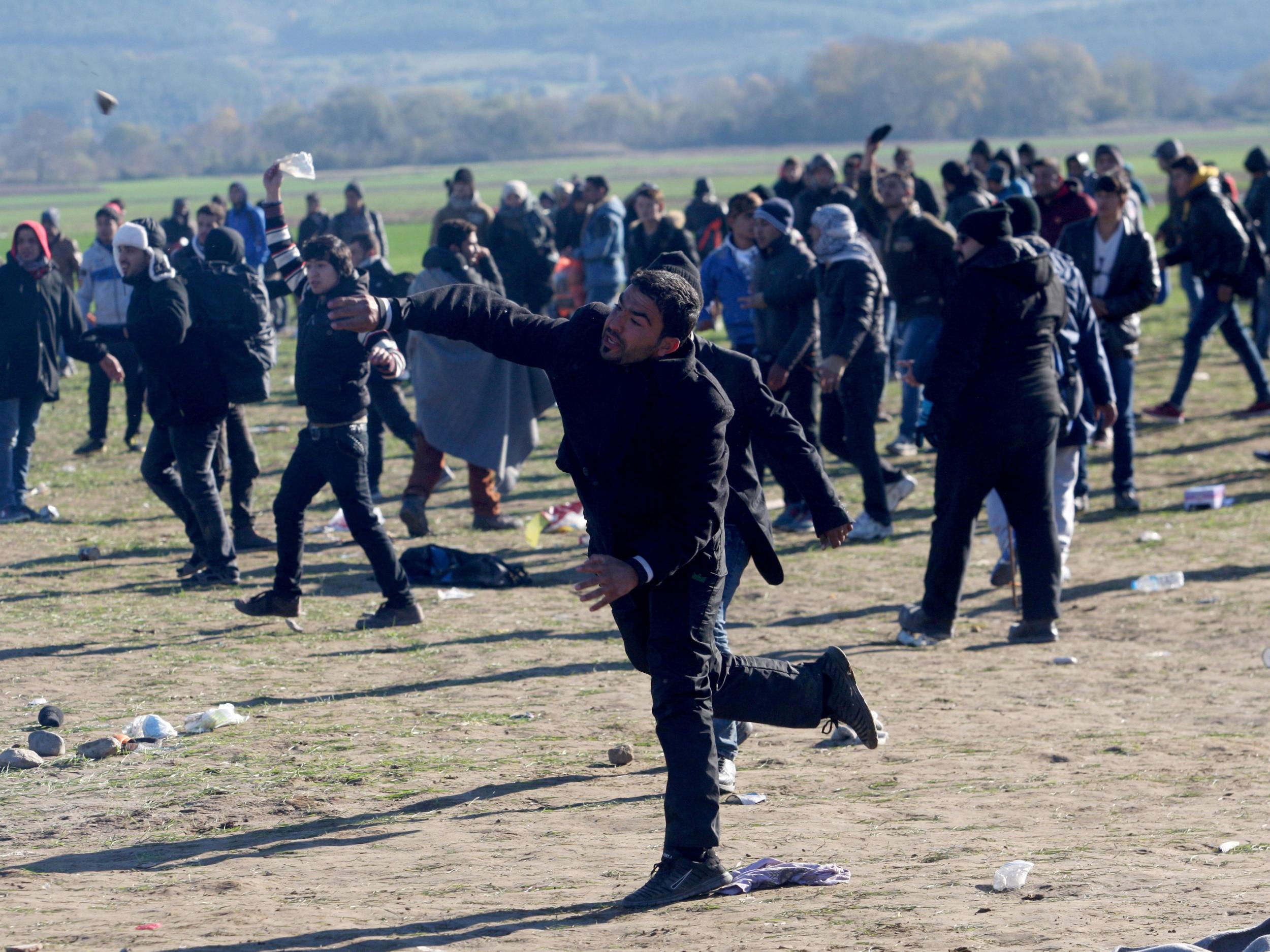 Refugees throw stones during clashes as they wait to cross Greek-Macedonia border Getty