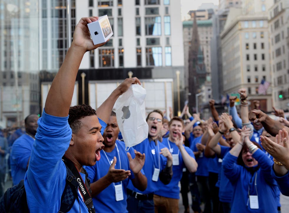 Brian Ceballo emerges from the Apple Store on Fifth Avenue as the first to purchase the new iPhone 5 to the cheers of Apple store employees September 20, 2013 in New York