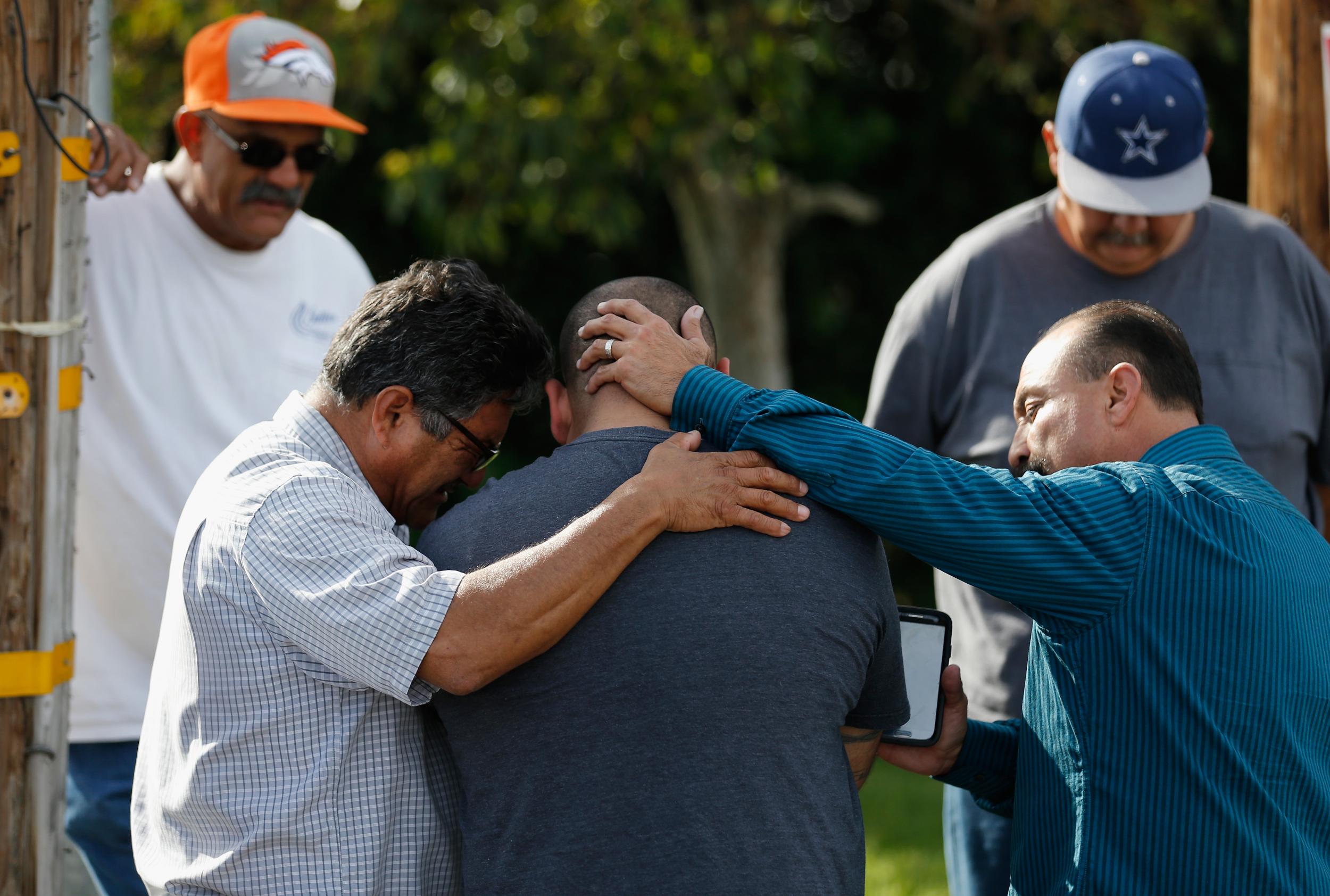 Men embrace outside the crime scene in San Bernardino.