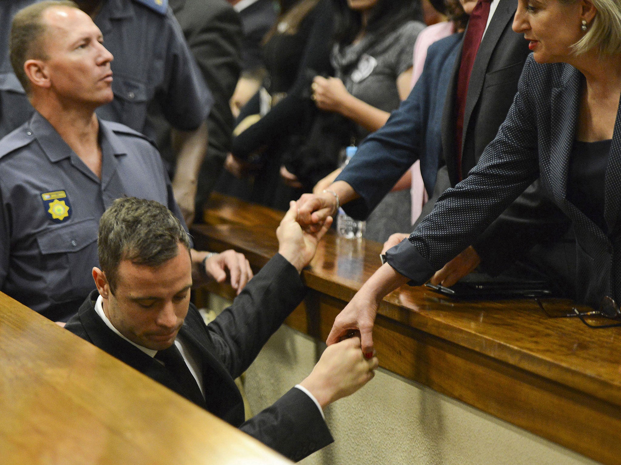 Oscar Pistorius touches hands with family members as he is led down to the cells of the court in Pretoria, South Africa to serve a five-year prison sentence for culpable homicide