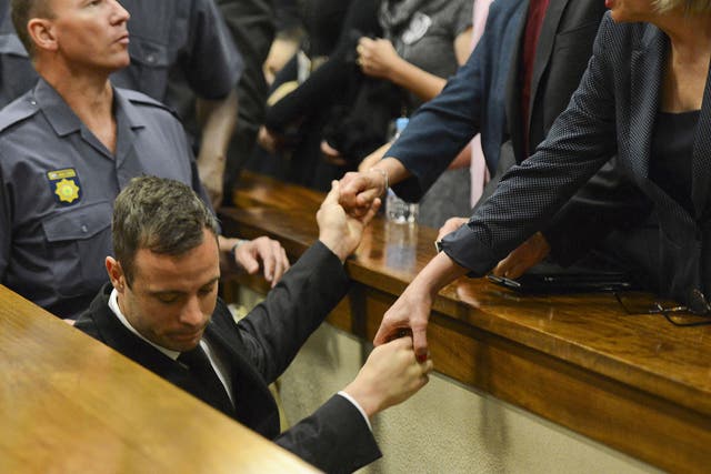 Oscar Pistorius touches hands with family members as he is led down to the cells of the court in Pretoria, South Africa to serve a five-year prison sentence for culpable homicide
