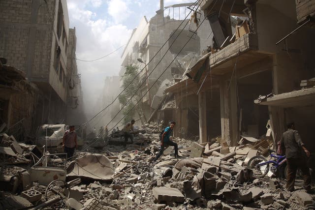 Syrians walk amid the rubble of destroyed buildings following reported air strikes by regime forces in the rebel-held area of Douma, east of the capital Damascus