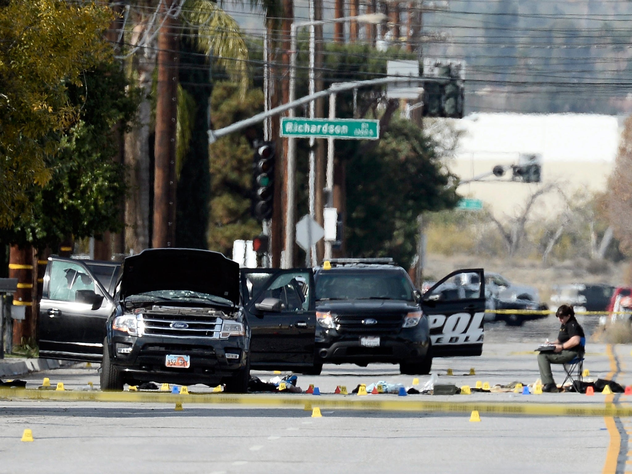 Evidence tags and debris surround the SUV thought to be the getaway vehicle of the husband and wife gunmen in the mass shooting