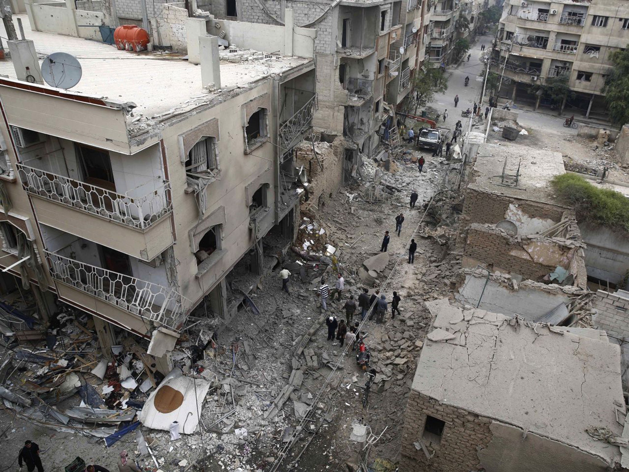 &#13;
Syrians inspecting damaged buildings following an air strike in Douma (Getty)&#13;