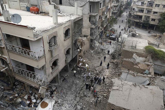 Syrians inspecting damaged buildings following an air strike in Douma