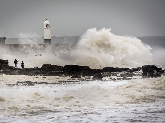 People watch waves close to the harbour wall at Porthcawl, South Wales, as Storm Desmond hits the UK