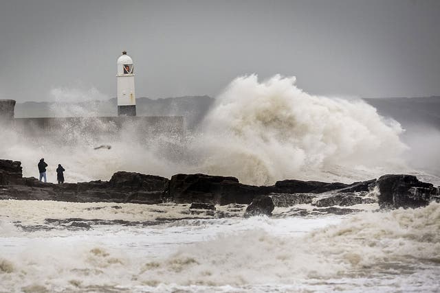 People watch waves close to the harbour wall at Porthcawl, South Wales, as Storm Desmond hits the UK