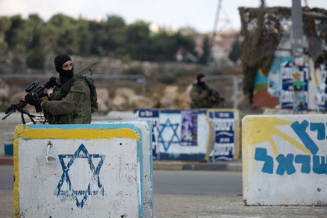 An Israeli soldier stands guard at a deserted junction between Jerusalem and Hebron