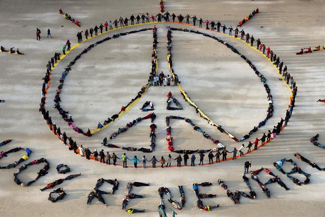 People make the "Pray for Paris" sign along with the slogan "100 percent renewable" in Paris, on the sidelines of the COP21 climate change conference