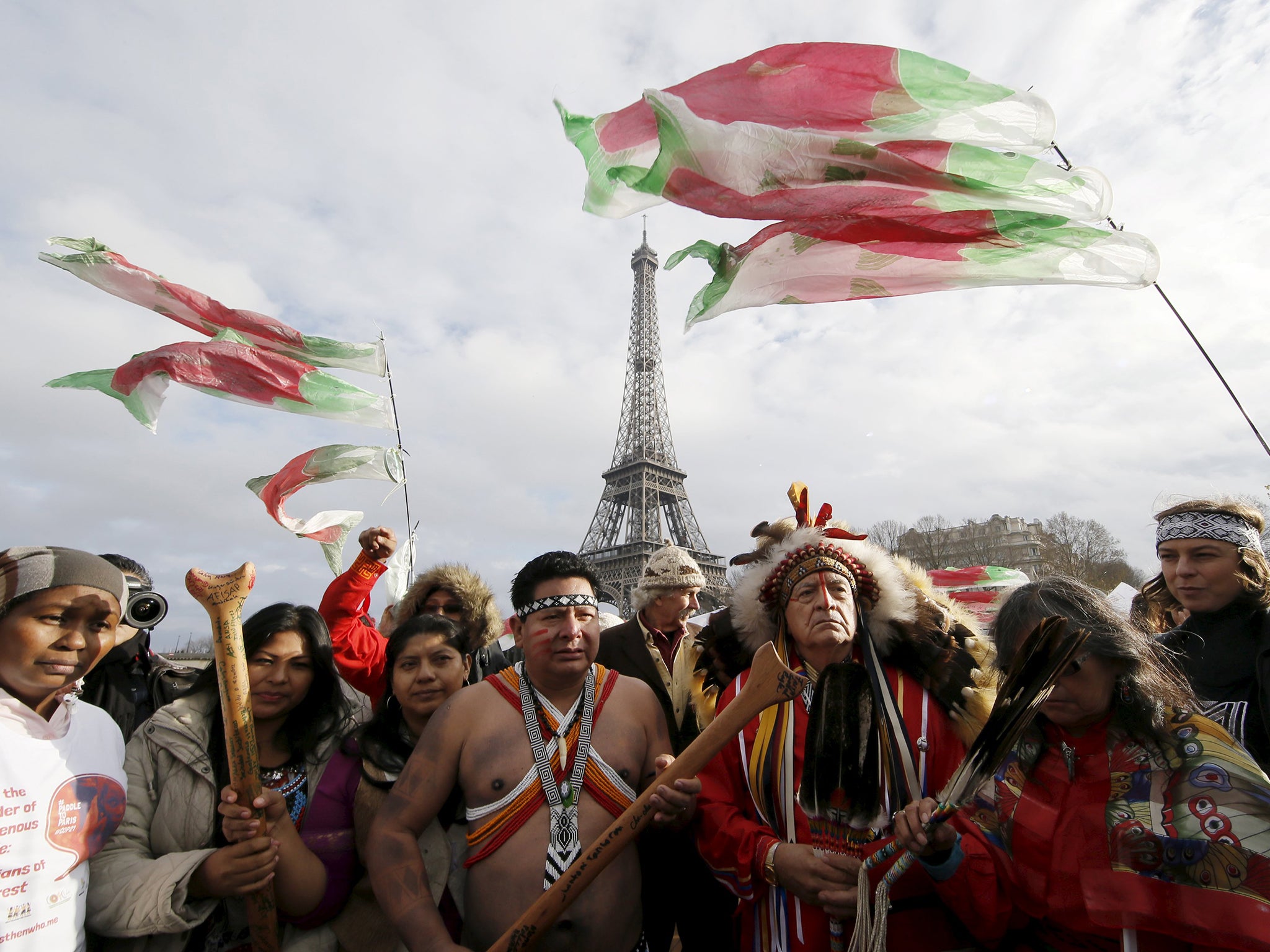 Indigenous leaders from all over the world pray as they sail on the Seine near the Eiffel Tower during a gathering demanding true climate solutions, in Paris, as the climate change conference (COP21) continues at Le Bourget near the French capital
