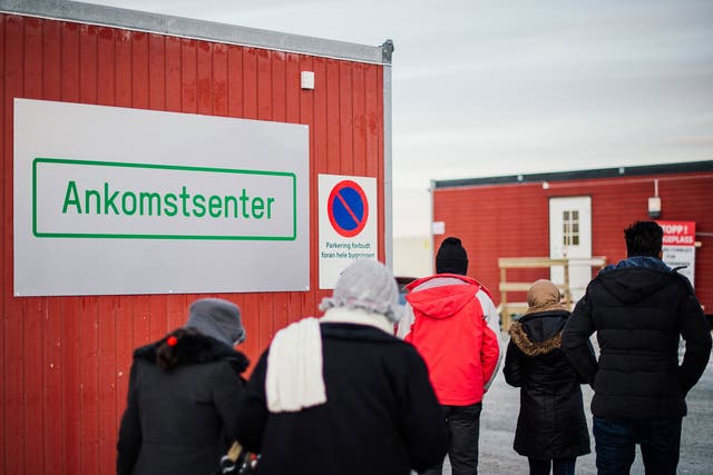 Refugees enter the arrival centre for refugees near the town on Kirkenes, northern Norway, close to the Russian - Norwegian border on November 12, 2015.