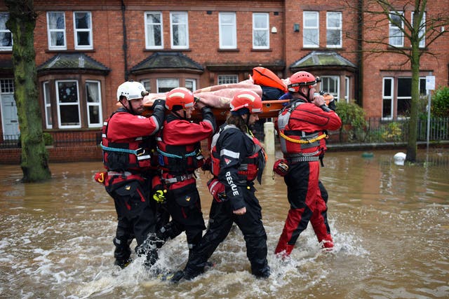 Members of the emergency services carry an elderly resident aloft as they rescue her from a flooded property in Carlisle