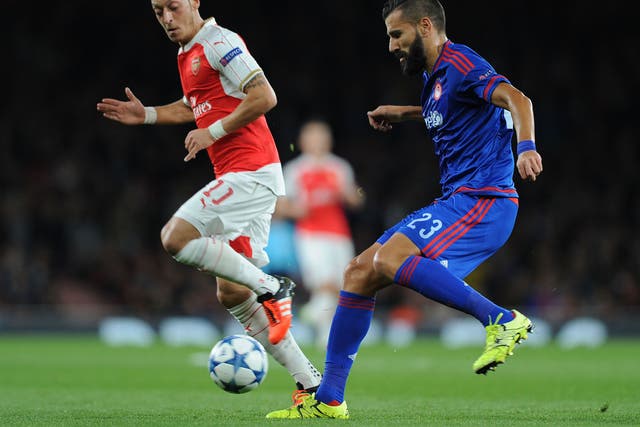 Arsenal's Mesut Ozil battles with Dimitris Siovas during the match with Olympiakos