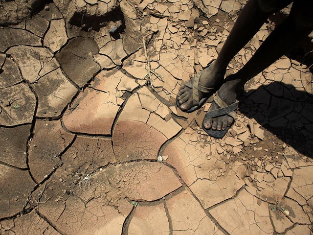 A young boy from a remote tribe in northern Kenya stands on a dried up river bed
