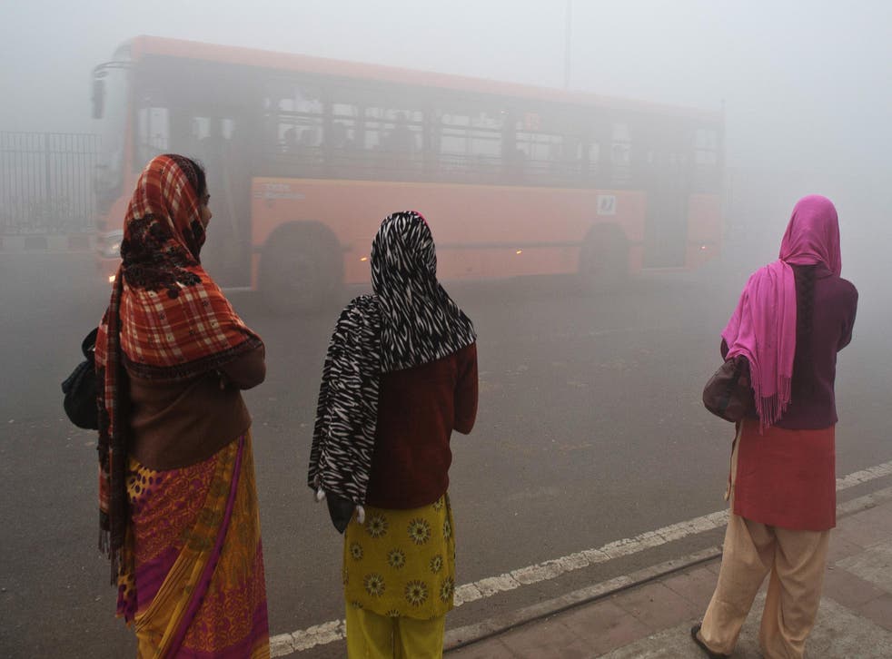 Commuters wait for a bus on a polluted Delhi morning in 2013