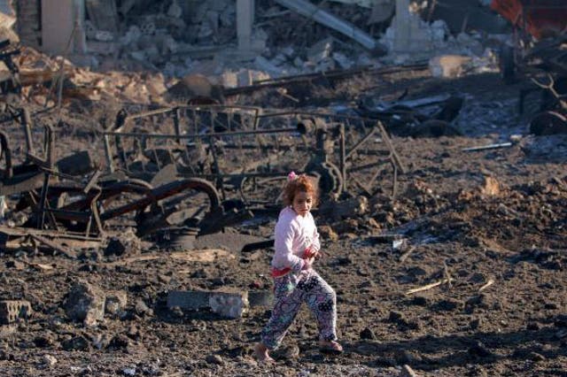 A girl walks over debris at a site hit by one of 3 three truck bombs