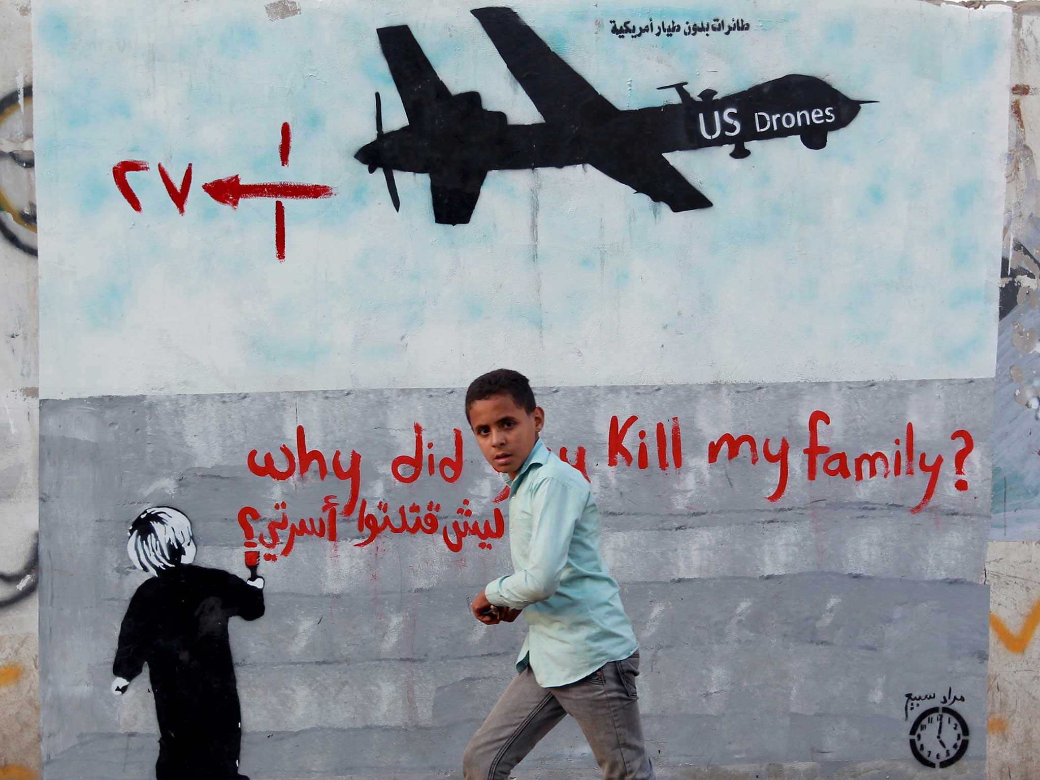 A Yemeni boy runs past a mural painted on the wall of the capital in Sanaa