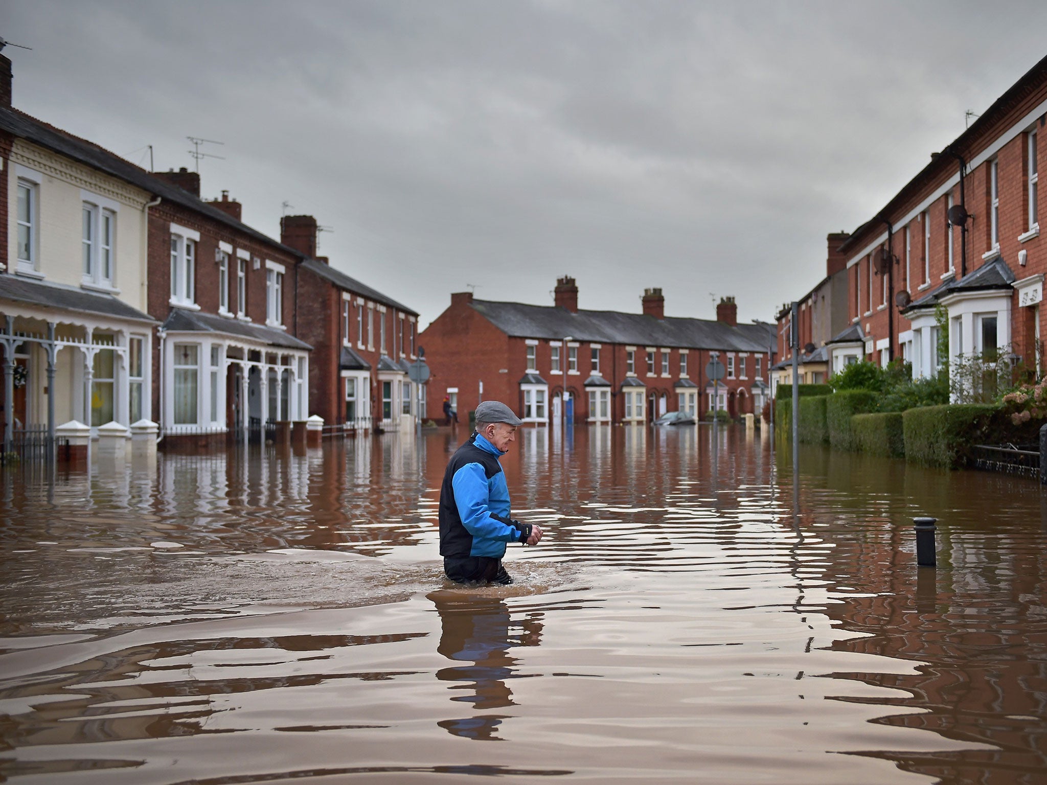 Local residents make their way through the flood water as they continue to leave their homes after severe flooding in Carlisle