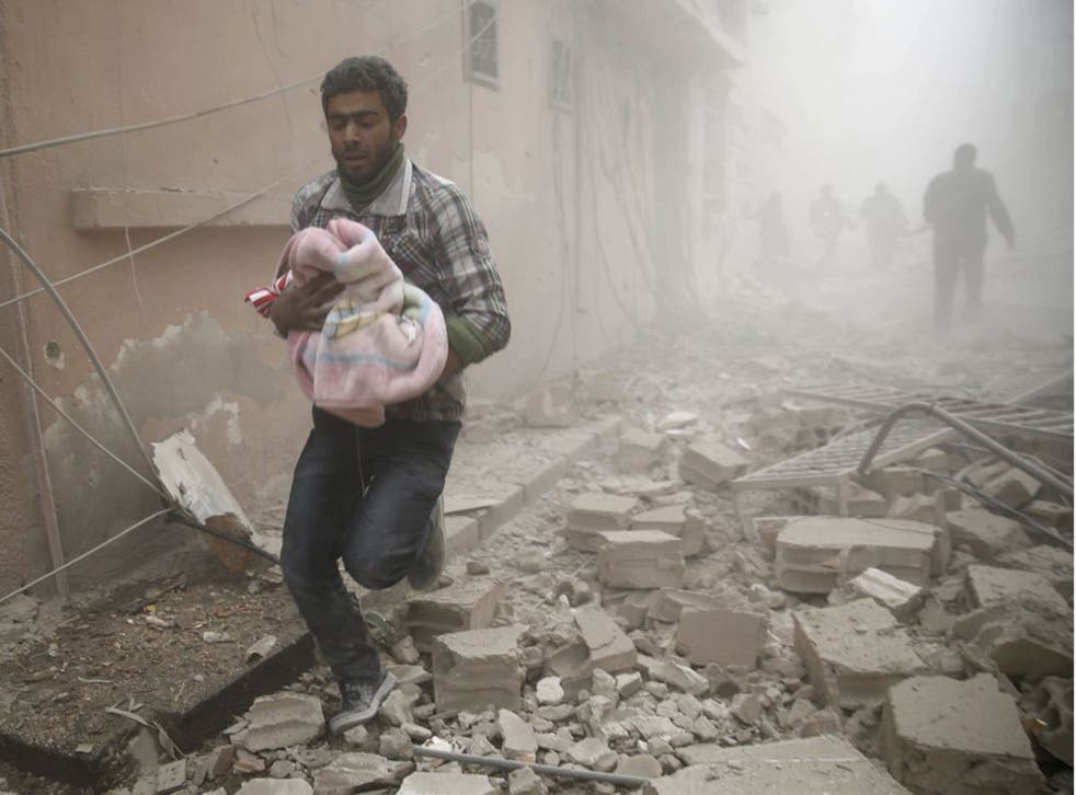 A Syrian man carries a baby wrapped in a blanket following air strikes on the town of Douma in the eastern Ghouta region, a rebel stronghold east of the capital Damascus, on 13 December, 2015