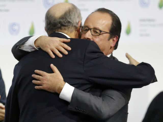French President Francois Hollande (R) embraces French Foreign Affairs Minister Laurent Fabius, President-designate of COP21