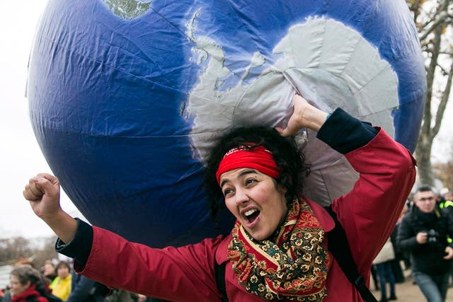 A demonstrator in front of the Eiffel Tower during COP21. The Paris Agreement creates a subtle but powerful mechanism to ratchet up the carbon-cutting commitments of all countries until they reach the point where global warming can indeed be held in check