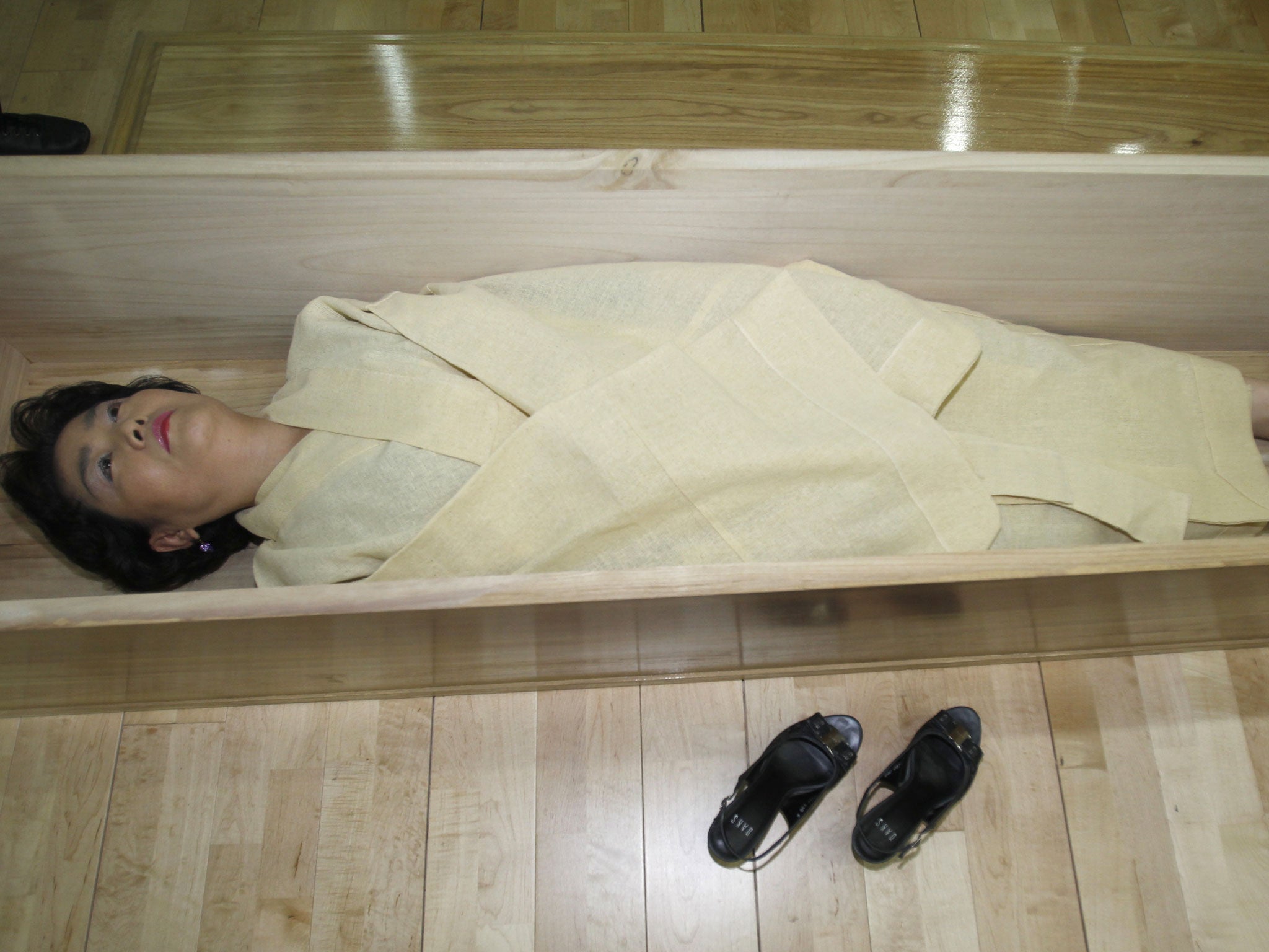 A woman, donning a traditional yellow hemp robe, lies down in a coffin during a "well-dying? course, run by a local district office in Seoul.The course, run by a local district office in the northeast of Seoul, has an aim: "Don't take life for granted." While some see the mock funeral as a way to reflect on one's life and prepare for death, many sceptics still question whether death simulation can prevent suicide and blame some entrepreneurs for using this as a commercial event