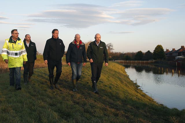 British Prime Minister David Cameron, centre, looks at the flood defence system in Carlisle as residents began sweeping out homes and businesses in the wake of Storm Desmond
