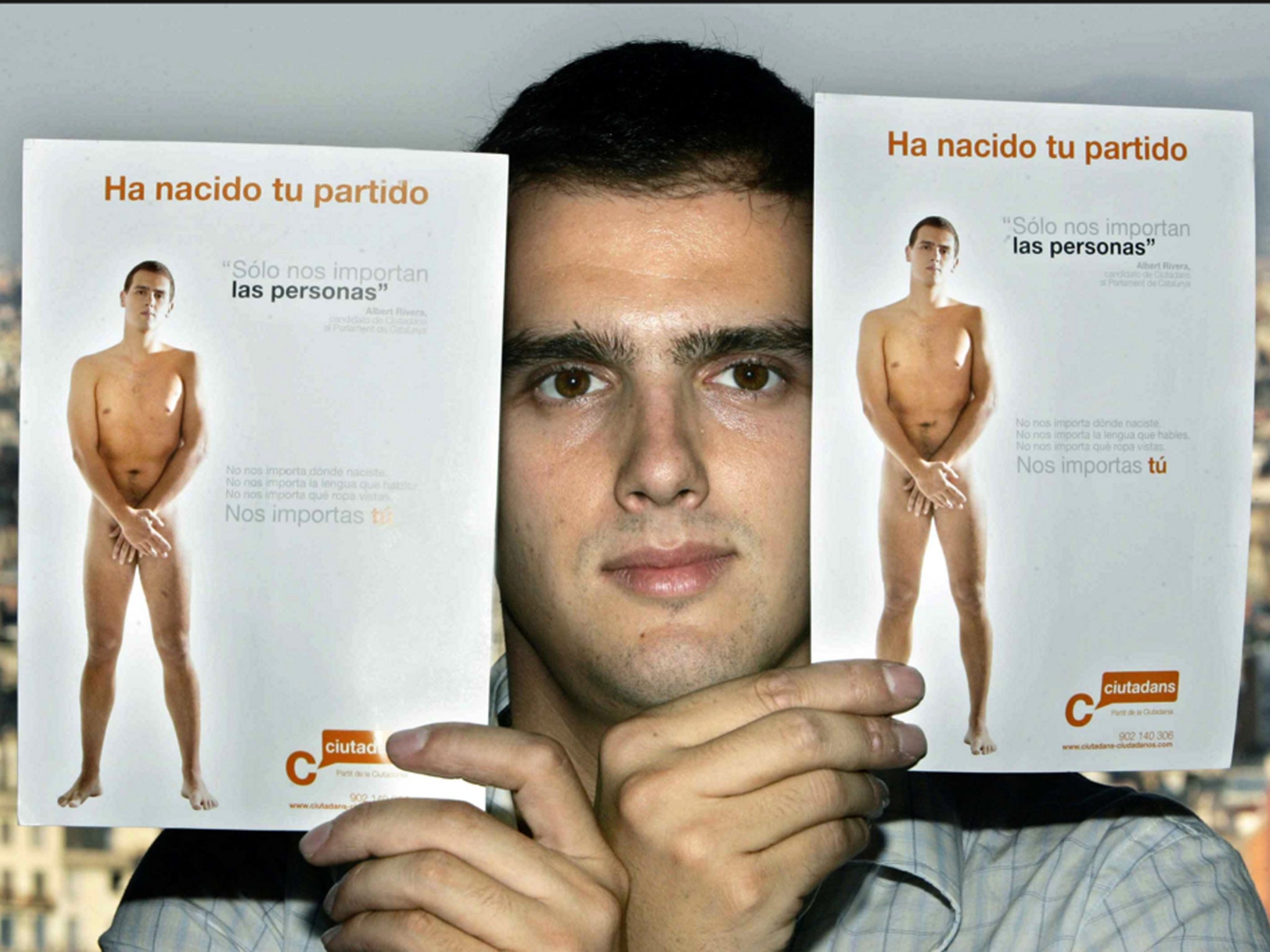 Albert Rivera, launching his new party, holds up campaign posters for which he posed naked, in Barcelona