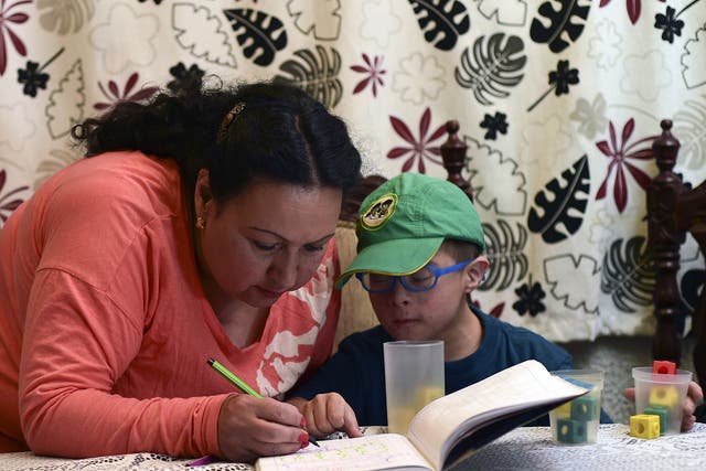 Colombian priest Aida Soto helps her son with his homework in Bogota on March 5, 2015. Soto is one of four Latin American women priests, member of the Roman Catholic Women Priests Association