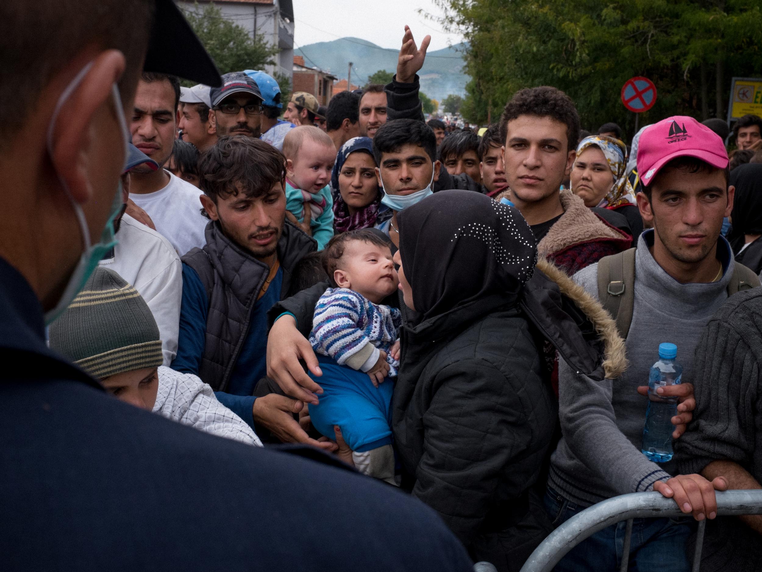 Serbia. A woman holds a small child as she queues at a reception centre for refugees and migrants