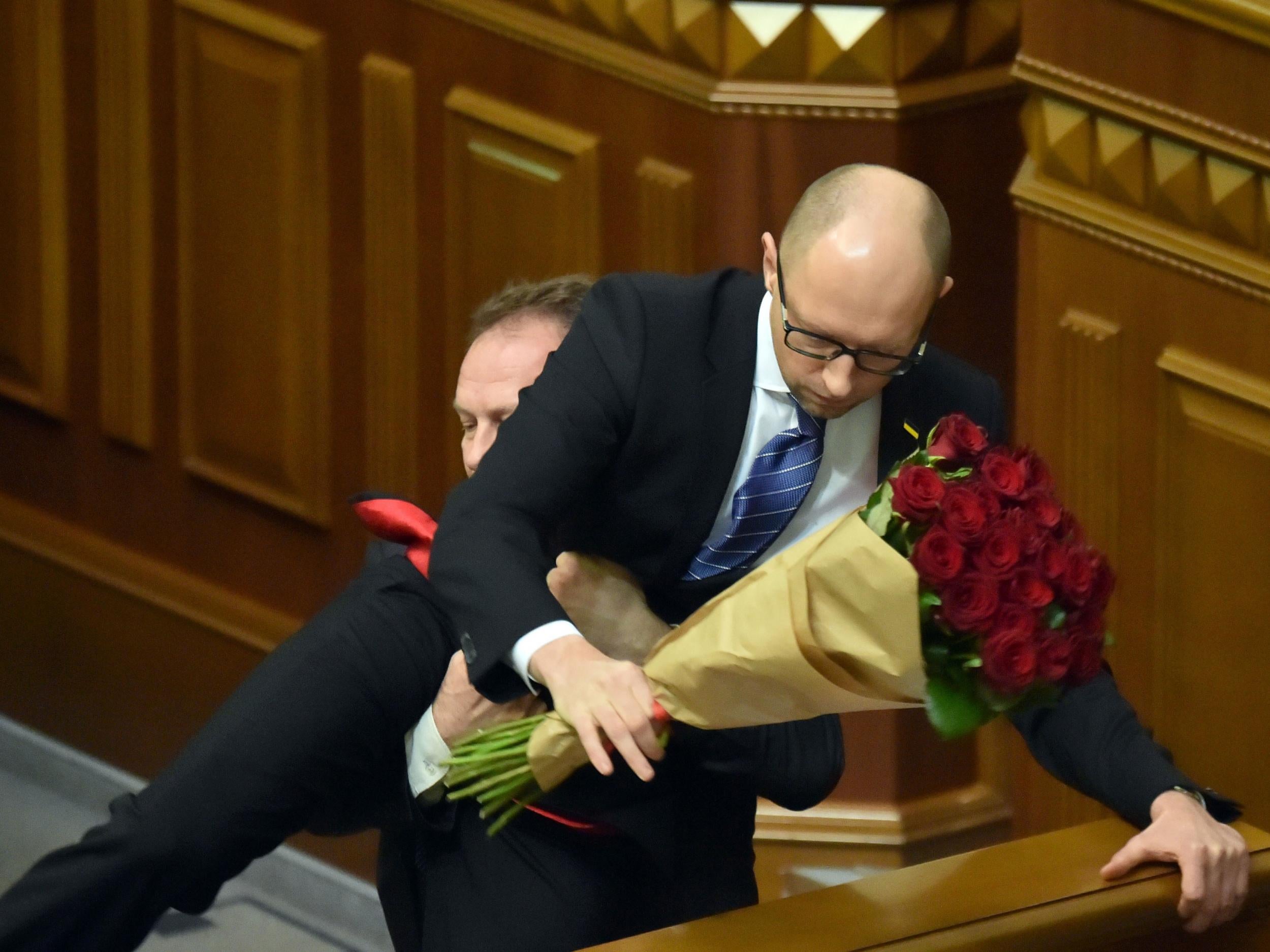 Rada deputy Oleg Barna removes Prime Minister Arseny Yatseniuk from the tribune, after presenting him a bouquet of roses, during the parliament session in Kiev