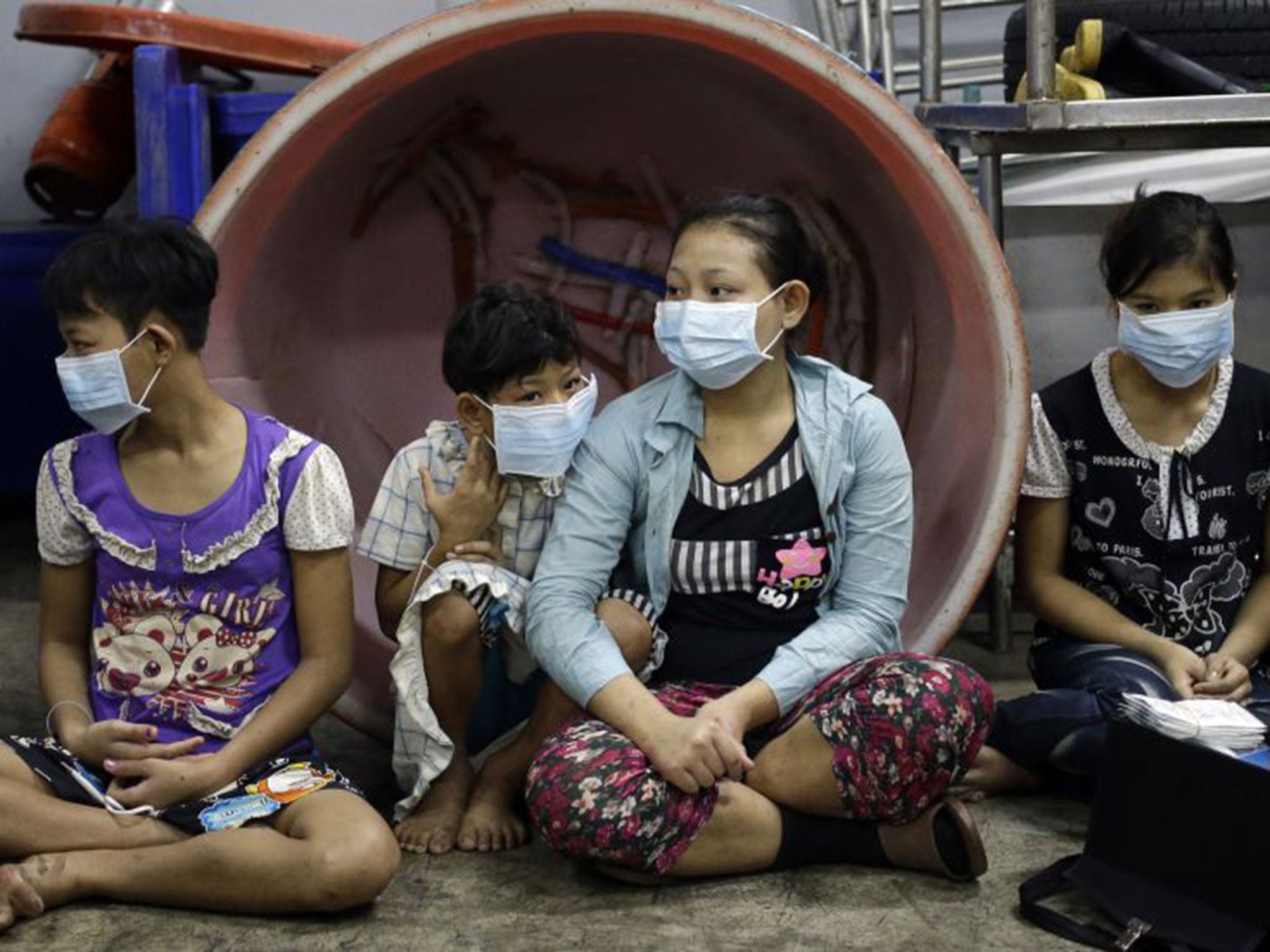 Eae Hpaw, 16, center, an undocumented child worker, sits with children and teenagers to be registered by officials during a raid on a shrimp shed in Samut Sakhon, Thailand.