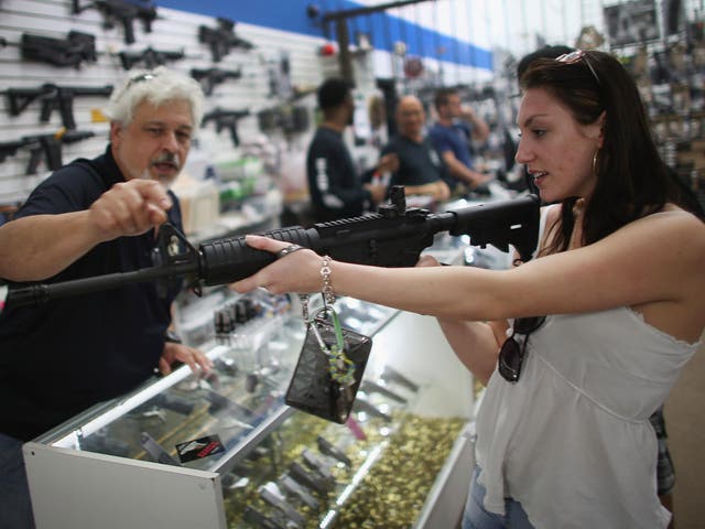 A co-owner of the National Armory gun store, helps Cristiana Verro consider fire arms on April 11, 2013 in Pompano Beach, Florida