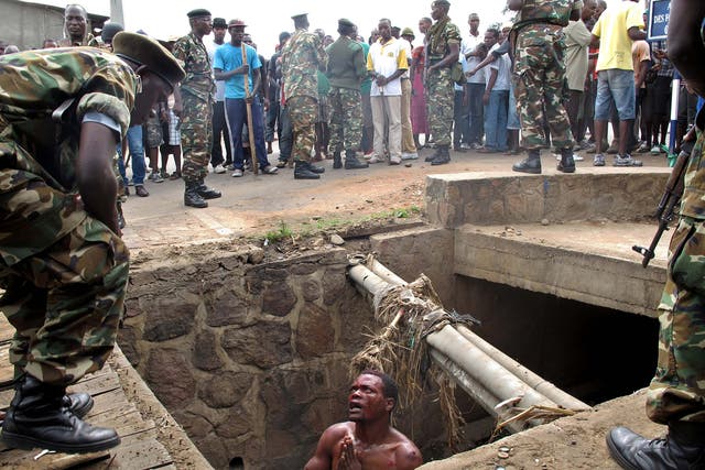 A man begs for help from the military after escaping a lynch mob during clashes in Burundi, 2015