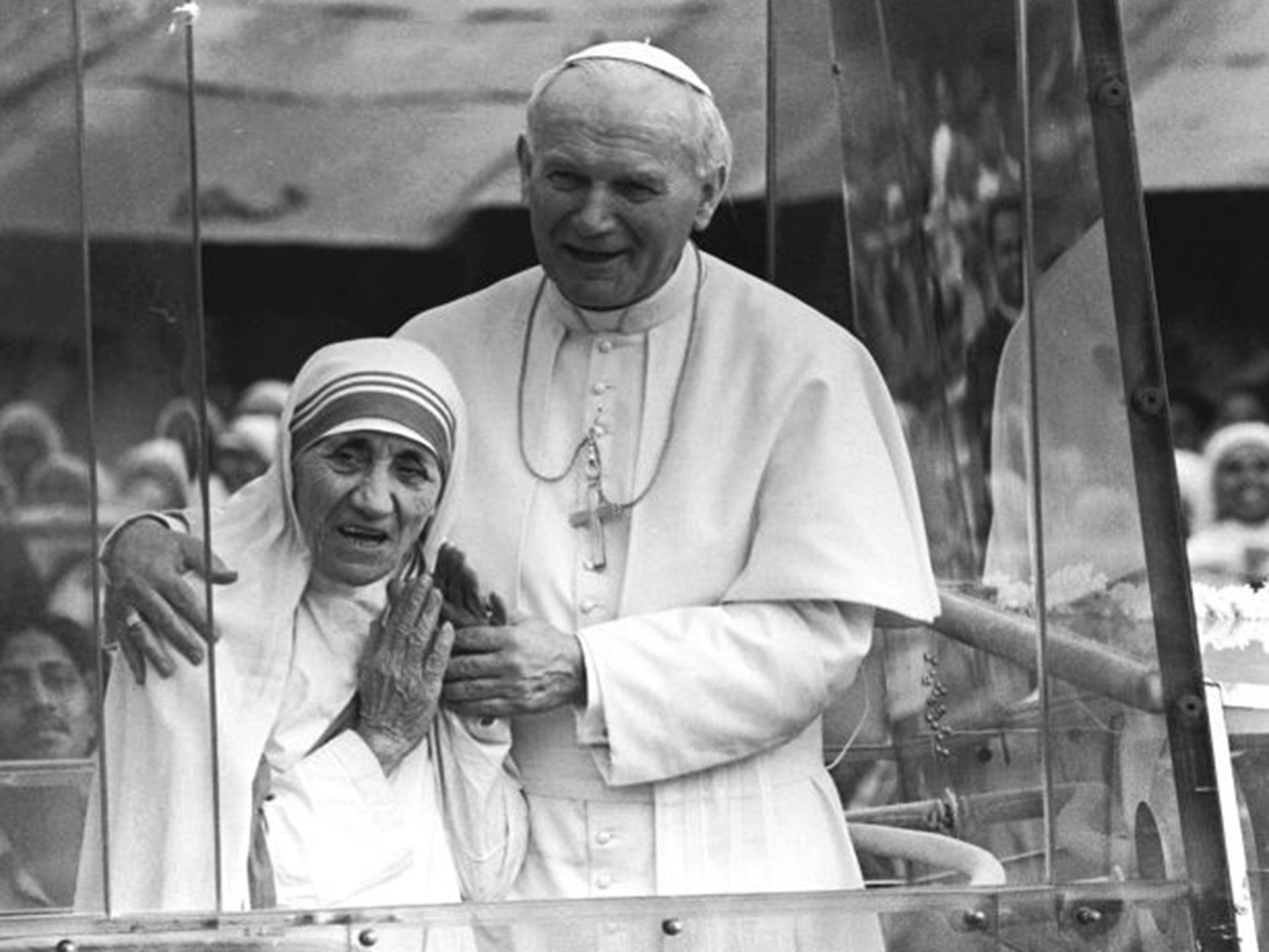 Pope John Paul II holds his arm around Mother Teresa as they ride in the Popemobile outside the Home of the Dying in Kolkata