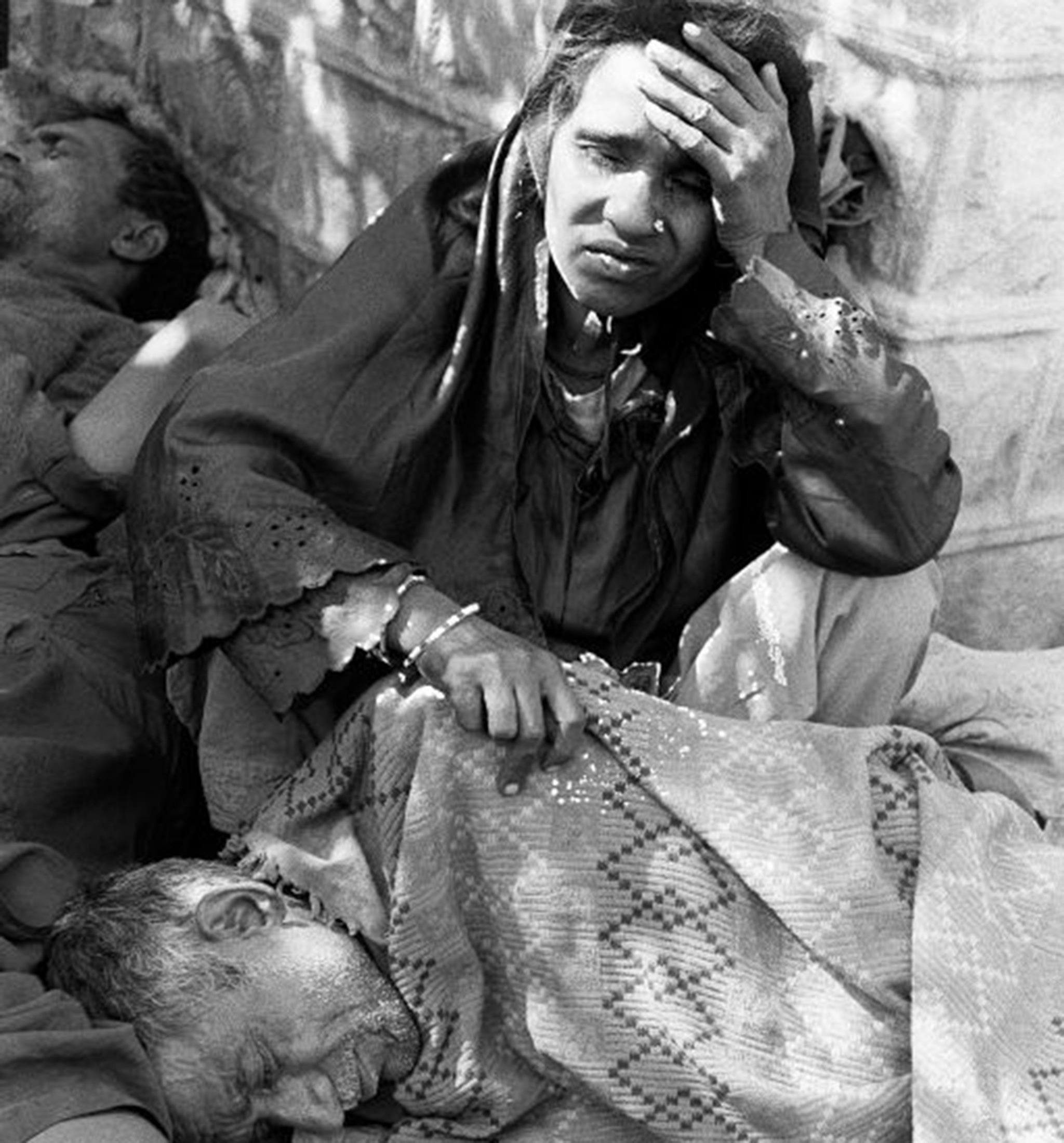 Blinded victims of the Bhopal tragedy sit in the street and wait to be treated on December 4, 1984