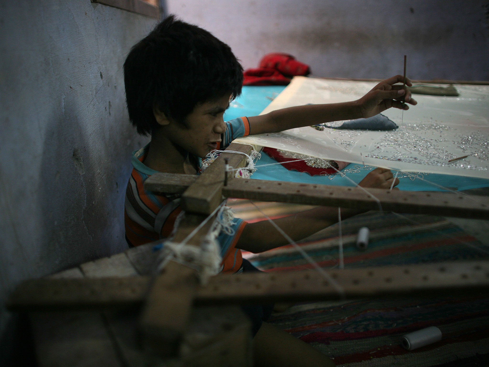 An Indian child sews sequins on to a garment in a workshop in Delhi. Currently, children under 14 are allowed to work in ‘non-hazardous’ occupations