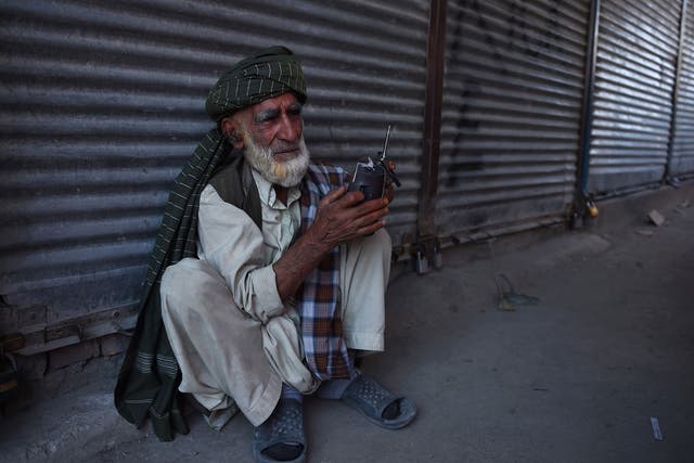 An elderly Afghan man listens to a radio early in the morning in Kabul on 16 July, 2015
