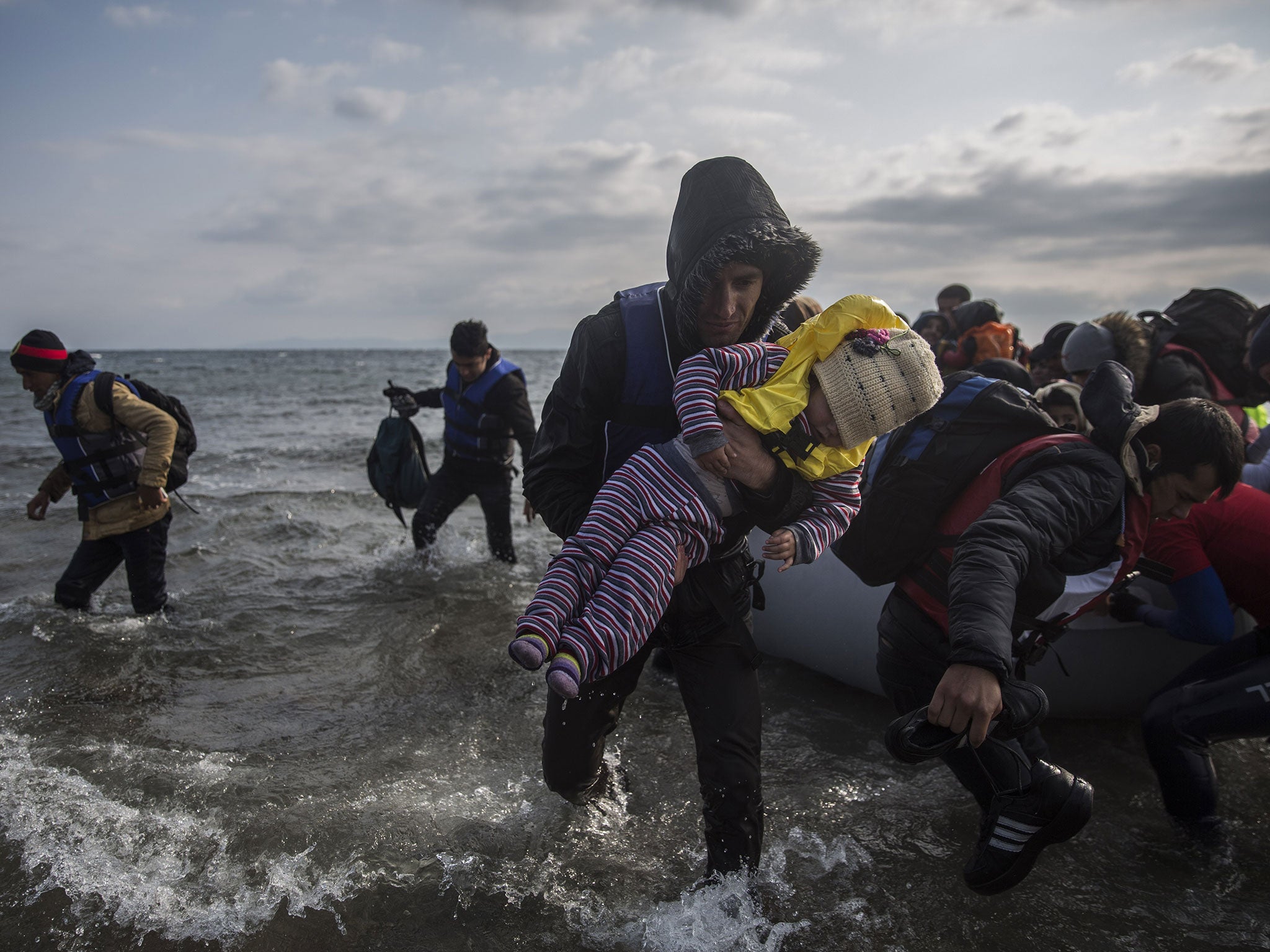 Refugees disembark from a dinghy after their arrival from Turkey on the Greek island of Lesbos, on Saturday, Dec. 12, 2015