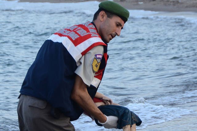 A Turkish police officer carries the body of Aylan Kurdi off the shores in Bodrum