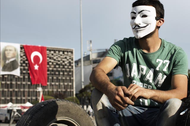 A man wearing an Anonymous-style Guy Fawkes mask sites in Taksim Square in Istanbul during 2013's anti-government protests