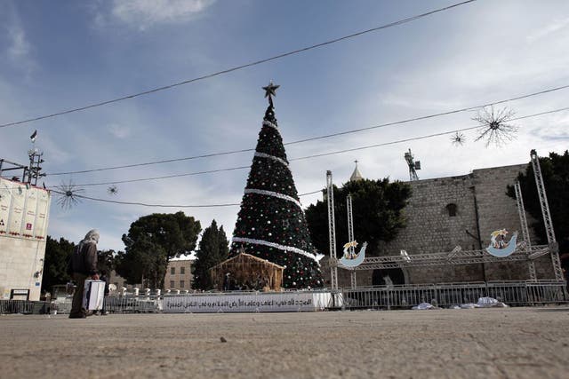 A man walks past a Christmas tree on the Manger Square
