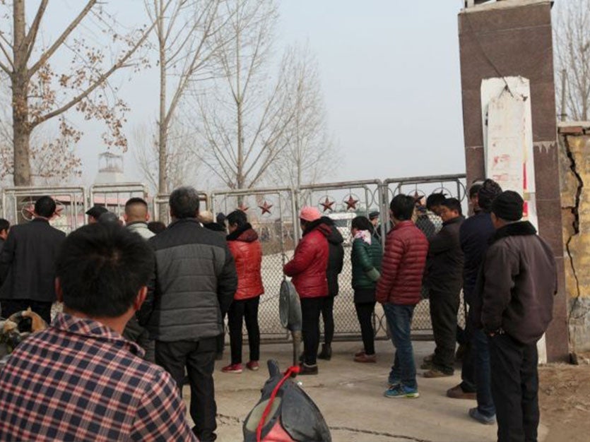 People stand outside the gypsum mine after it collapsed on Friday morning, in Pingyi, Shandong province