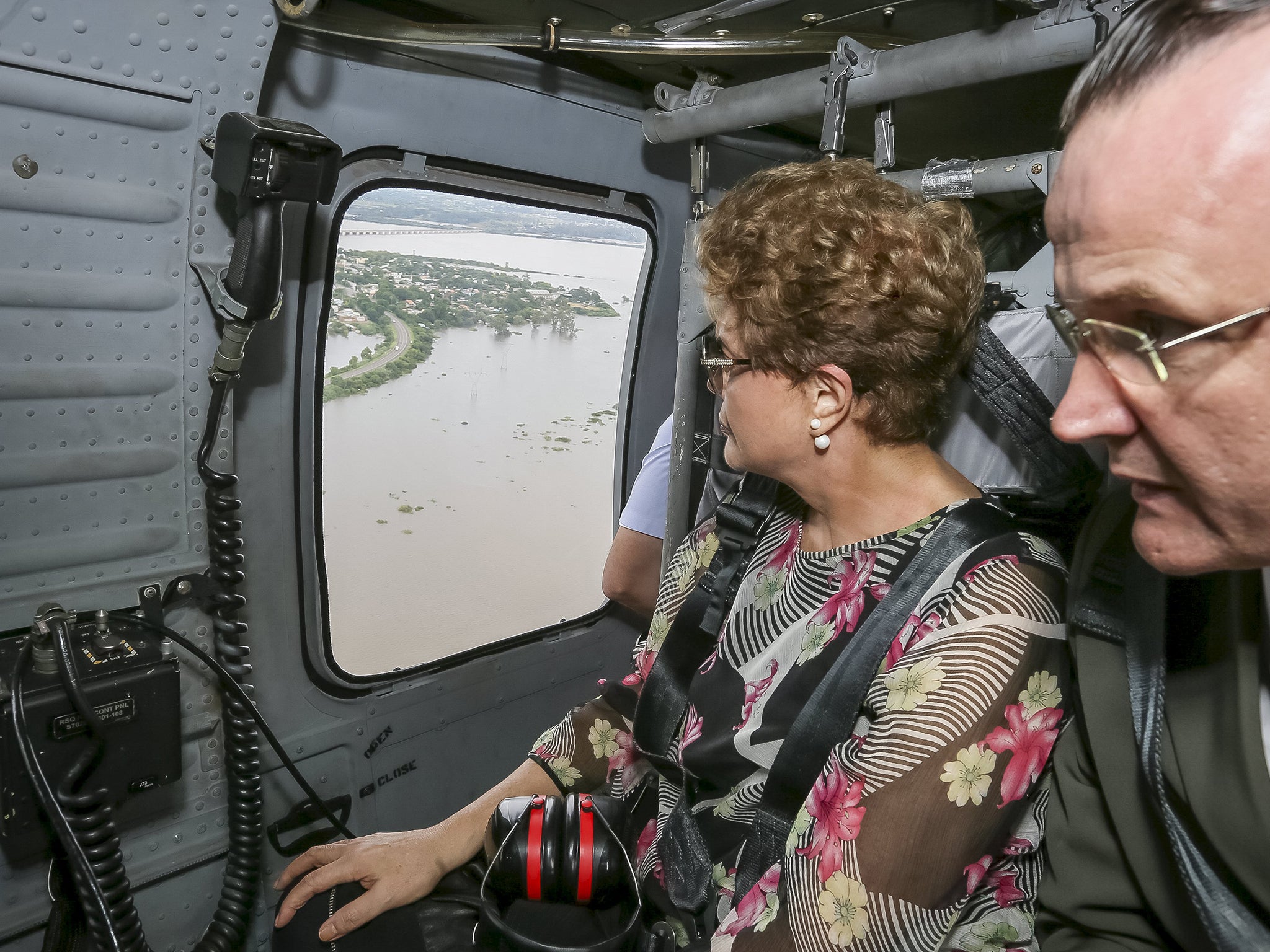 Brazil's President Dilma Rousseff looks out of a plane during a flight over the areas hit by floods