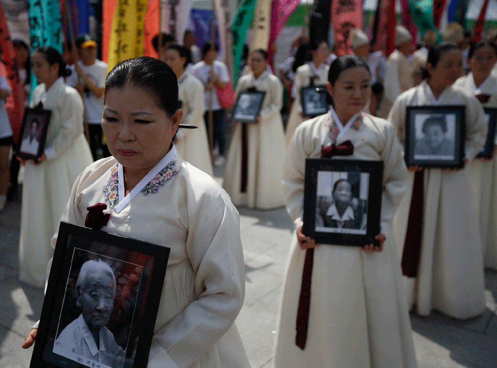 Participants carry the portraits of Korean women who were made sex slaves by the Japanese military during World War II, during a requiem ceremony in central Seoul August 14, 2013.