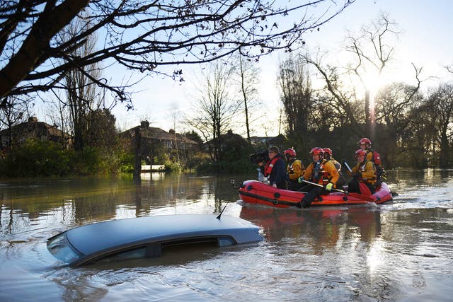 Members of the emergency services paddle down Huntington Road past a submerged parked car after the adjacent River Foss burst it's banks in York. The government was holding emergency talks Sunday as flooding in northern England forced hundreds of people to leave their homes, including in the historic tourist destination of York.