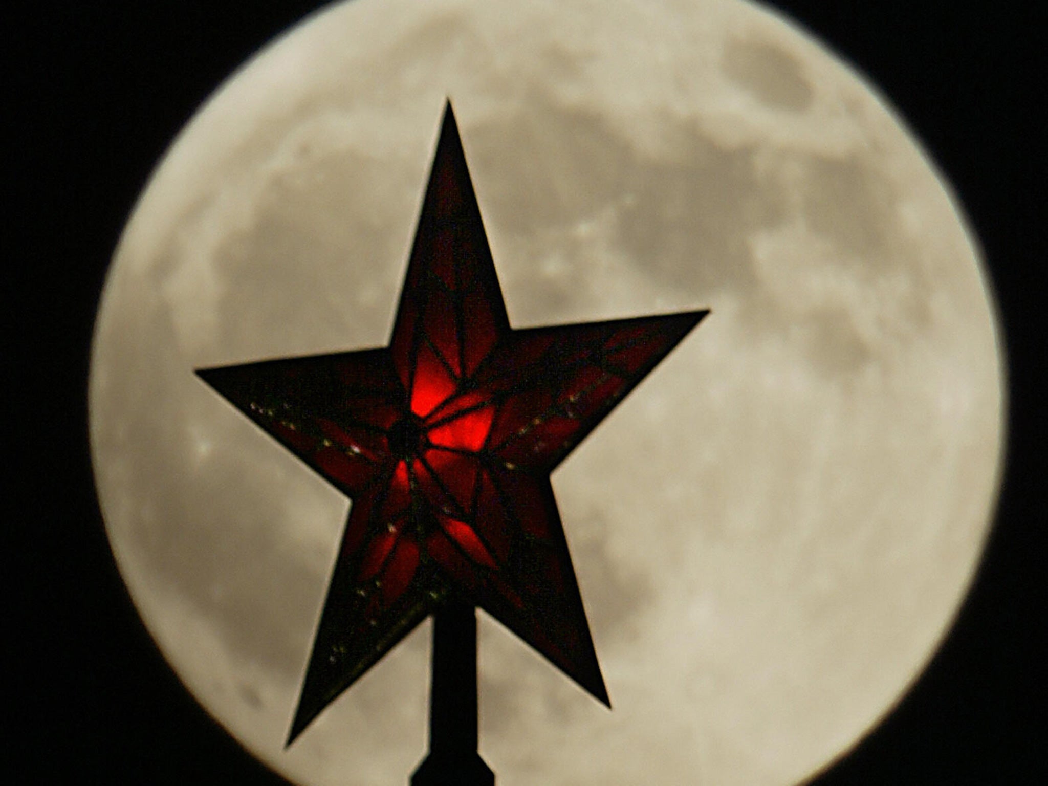 One of the Ruby stars of the Kremlin towers in Moscow is silhouetted by a full moon
