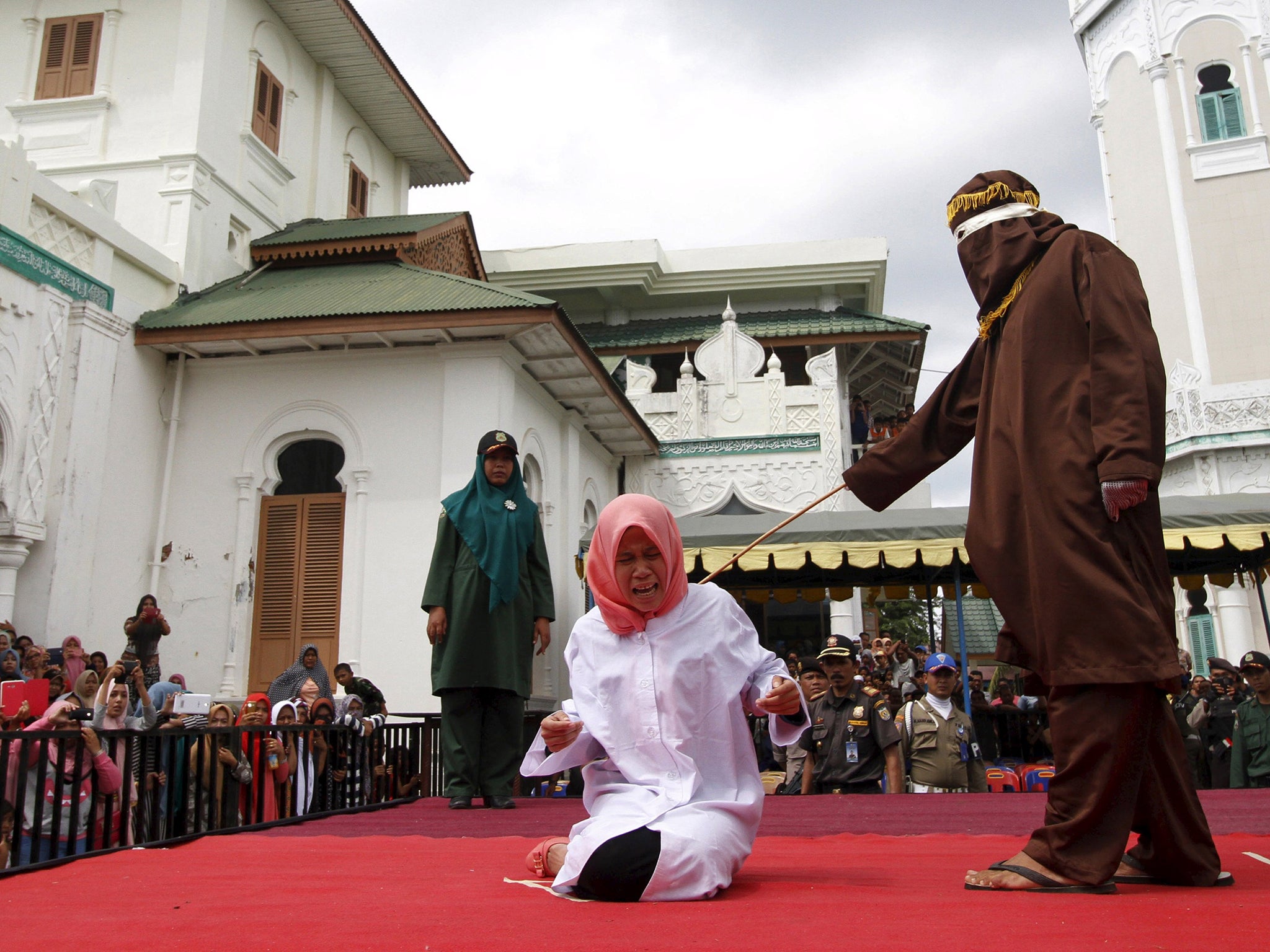 Nur Elita screams during caning as part of her sentence in the courtyard of Baiturrahman mosque in Banda Aceh, Indonesia's Aceh province