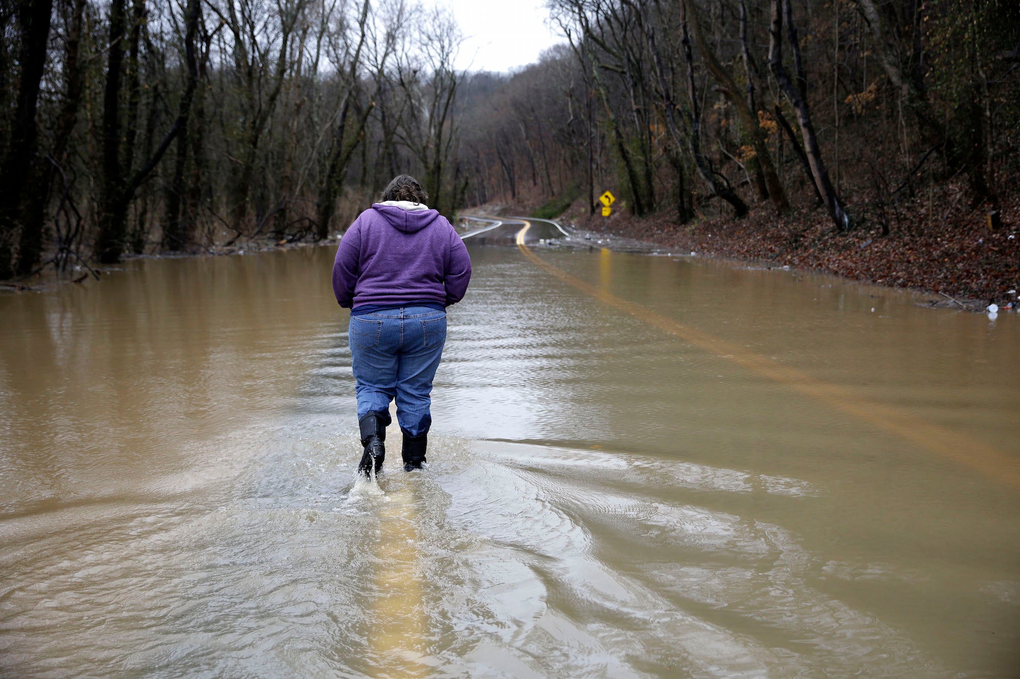 Tammy Poirrier walks down a flooded road to get back to her home before evacuating on December 28, 2015, in Eureka, Missouri.