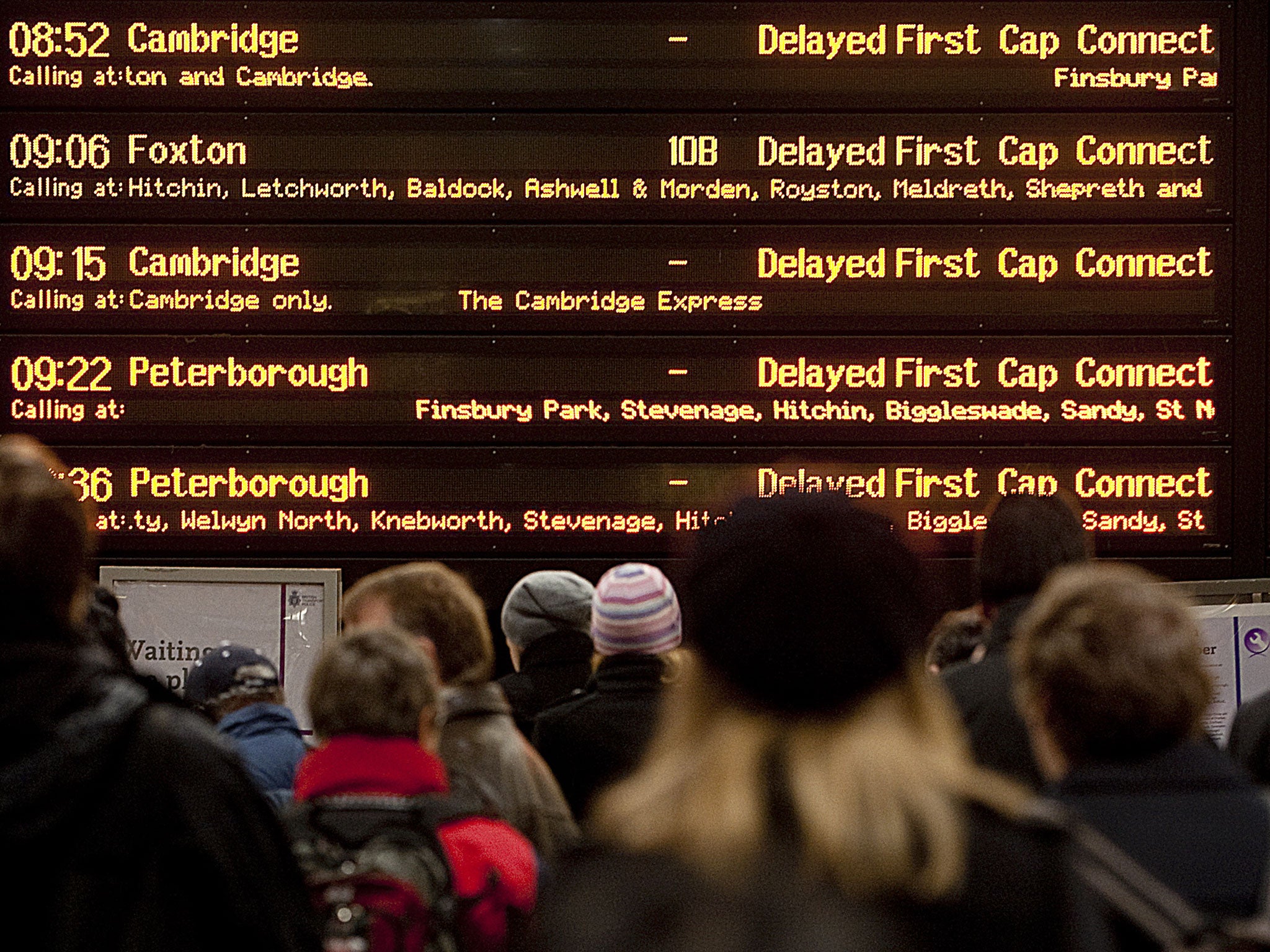 Rail passengers look at the departures screen in Kings Cross station in London, as trains are delayed on December 18, 2009